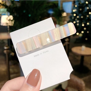 Gros plan sur la pince à cheveux rectangulaire rayée aux reflets nacrés pastels