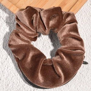 Detail of dark brown velvet scrunchie with hidden zipper pocket and ribbed texture
