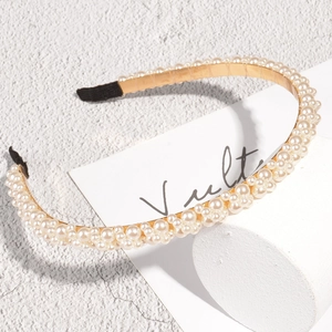 Elegante dunne gouden haarband met witte parels op een minimalistische witte basis