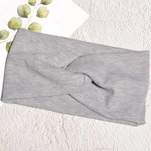 Dettaglio di fascia per capelli in maglia grigio chiaro con nodo incrociato e trama a coste