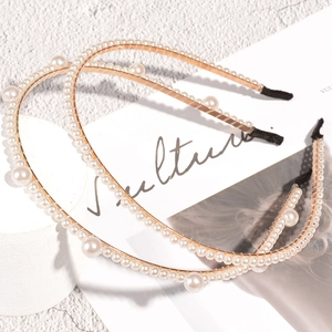 Elegante set van twee gouden haarbanden met parels op witte getextureerde achtergrond