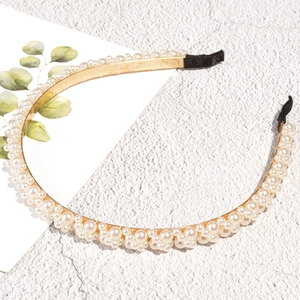 Detailweergave van gouden metalen haarband met parels op een getextureerde rots