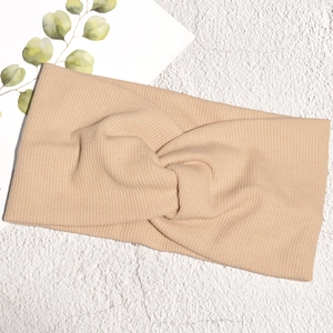 Dettaglio della fascia in maglia beige con nodo a incrocio e trama a costine morbida