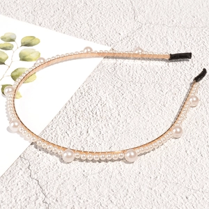 Detail van een elegante gouden haarband met fijne witte parels en zwarte beschermtips