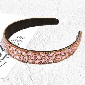 Close-up of luxury pink rhinestone leaf headband with golden beads and black fabric lining