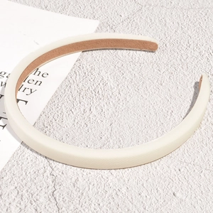 Detail showing cream satin padded headband with brown non-slip lining on textured background