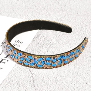 Detailed macro view of blue marquise rhinestones and gold beads on the leaf headband