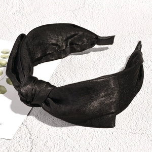 Detailed macro view of black satin fabric texture and top knot design on wide headband