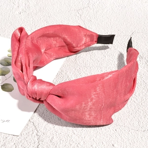 Detailed view of pink satin knotted headband with elegant shimmering fabric texture