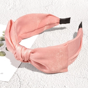 Detail view of pink satin knotted headband with smooth lustrous silk texture