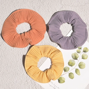 Three pleated candy-colored striped hair scrunchies in orange, purple, and yellow tones