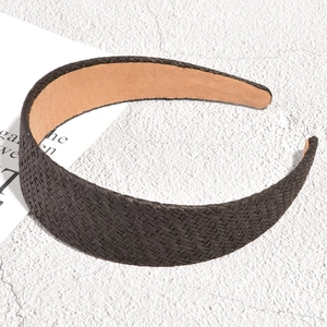 Detail shot of a wide braided raffia headband in dark brown with smooth woven textures