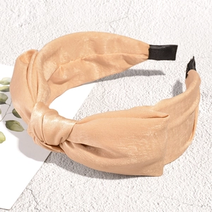 Detail of champagne satin knot headband featuring a silky texture and wide twisted design
