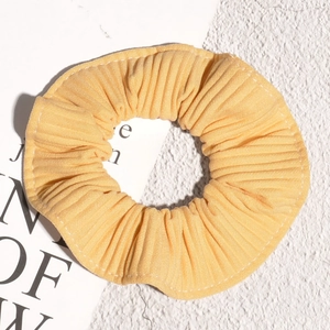 Macro detail of yellow pleated chiffon hair scrunchie with fine vertical textures