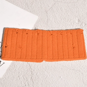 Gros plan détaillé du bandeau en coton tricoté orange vif sur un fond texturé rustique