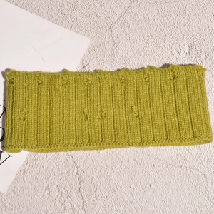 Détail macro du bandeau en maille vert avocat avec texture en laine vintage et nœuds