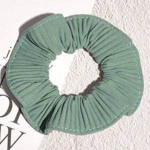 Detail view of the sage green pleated scrunchie with fine texture and stitching