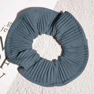 Detailed view of blue-grey striped fabric scrunchie with soft pleated texture and elastic design