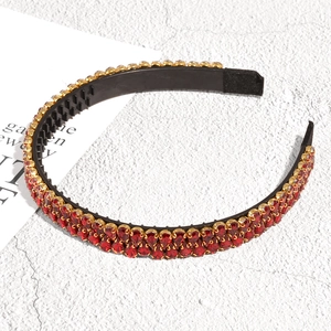 Détail de strass rouges en forme de poire sertis d'or sur un serre-tête antidérapant