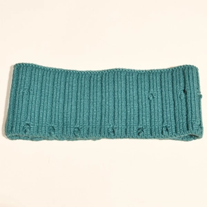 Détail du bandeau tricoté bleu canard avec texture côtelée et pompons décoratifs