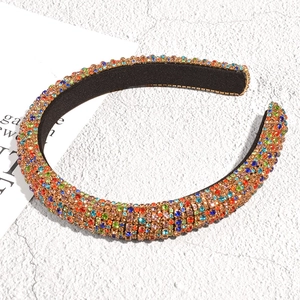 Close-up of wide velvet headband with colorful rhinestones on a marble background