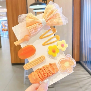 Dettaglio di un set da 8 pezzi con fermagli per capelli a fiori arancioni ed elastico per bimba