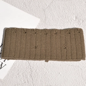 Détail d'un bandeau en tricot marron avec texture côtelée et petits nœuds décoratifs