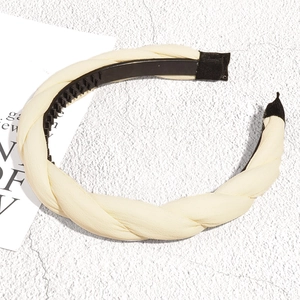 Detail view of the cream braided headband featuring a non-slip toothed inner grip