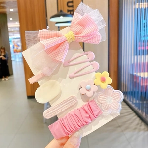 Dettaglio di fermagli per capelli con fiocco rosa e accessori floreali ricamati per bambine