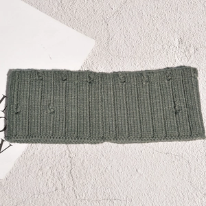 Détail du bandeau en maille gris-vert foncé avec texture à pompons et rayures