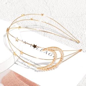 Detail view of gold wave headband with stars and pearl crescent moon on white background