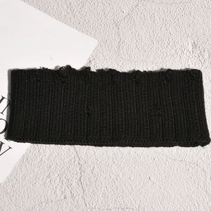 Détail d'un bandeau en maille noire avec textures déchirées sur fond de pierre