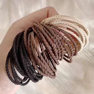 Detailed macro view of high-elasticity braided hair ties in neutral earth tones