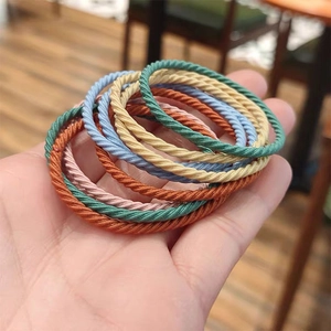 Close-up of hand holding colorful spiral woven elastic hair ties in various Morandi tones