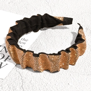 Close-up of luxury black pleated headband with sparkling golden rhinestones and texture
