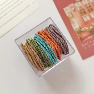 Detail of multi-colored braided elastic hair ties in a transparent storage box