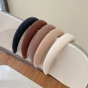Thick sponge headbands in five earth tones displayed on a curved white rack