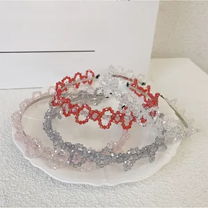 Détail de quatre serre-têtes en cristal faits main en rouge, rose, clair et gris sur plateau