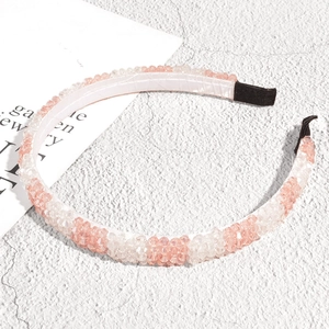 Detailed view of pink and clear crystal beads on a stylish headband with stone background