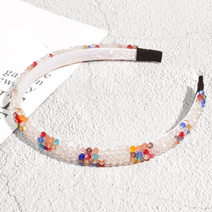 Detail of colorful crystal beaded headband with smooth white satin lining on stone