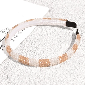 Detail of handcrafted crystal headband with champagne and white faceted beads on stone background