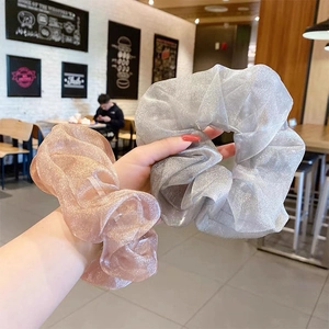 Nahaufnahme der silbergrauen und champagnerfarbenen Organza-Haargummis mit Glitzereffekt