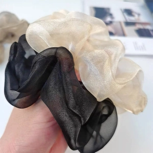 Nahaufnahme von schwarzen und champagnerfarbenen Organza-Haargummis mit Perlglanz