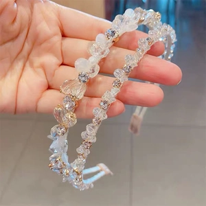 Détail de deux serre-têtes en cristal avec des strass étincelants et des perles blanches