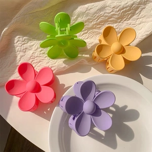 Detail of four matte flower hair clips in candy colors like neon green and pink