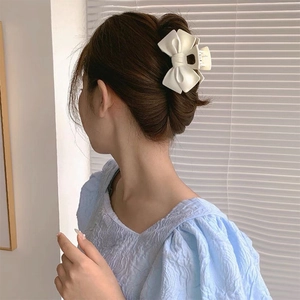 Détail d'une grande pince à cheveux nœud blanc crème sur un chignon élégant