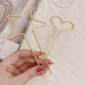 Gros plan d'épingles à cheveux minimalistes étoile et cœur dorées sur fond de tissu