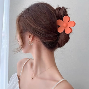 Close-up of matte orange flower hair claw clip worn on an elegant updo hairstyle