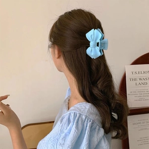 Vue détaillée d'une pince à cheveux nœud bleu clair mat sur les cheveux du modèle