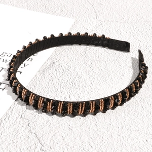 Detail of beaded headband with black faceted crystals and rose gold seed beads on fabric